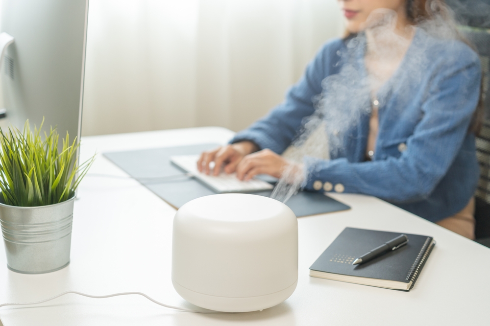 Modern,Air,Humidifier,Device,During,Sitting,Workplace,,Happy,Asian,Young